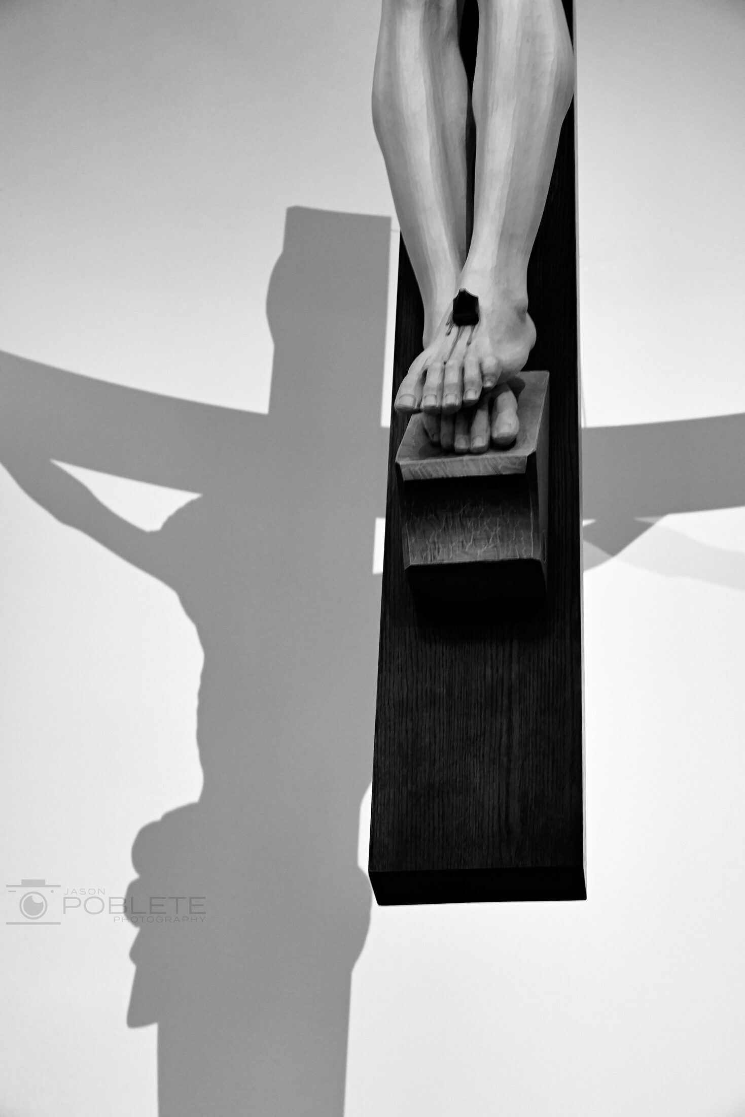 A small religious figure in a wall niche casts a long shadow.