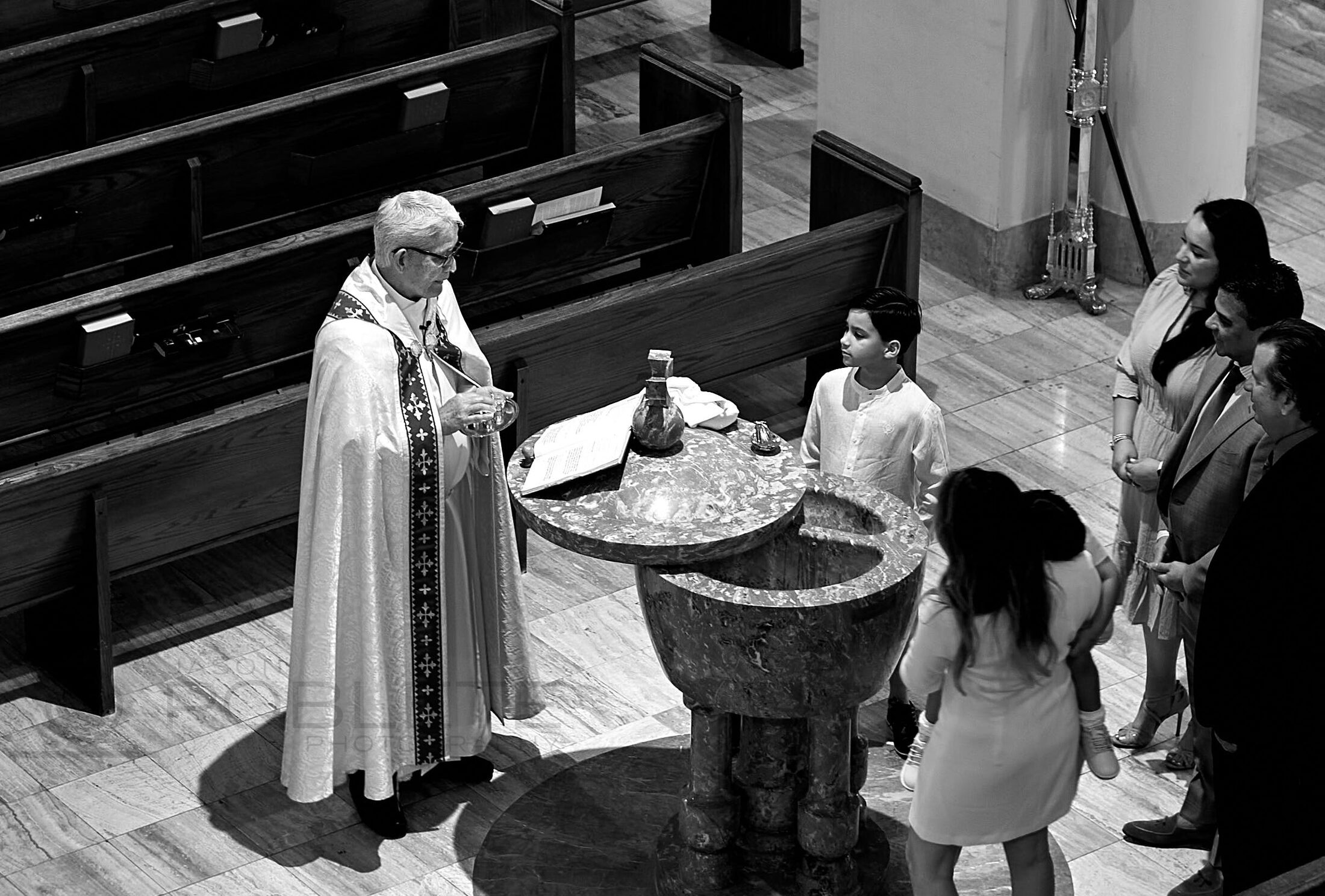 A priest conducts a ceremony before a small congregation.