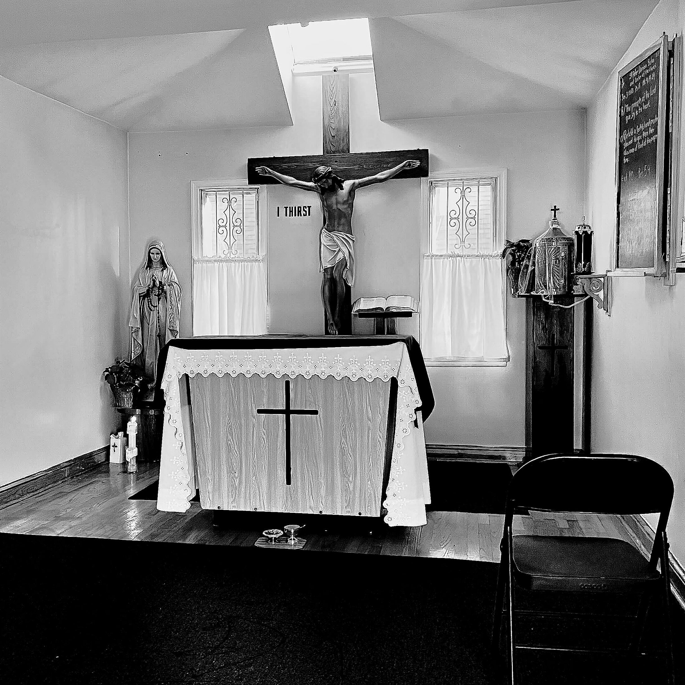 An altar and cross stand in a modest, empty chapel.