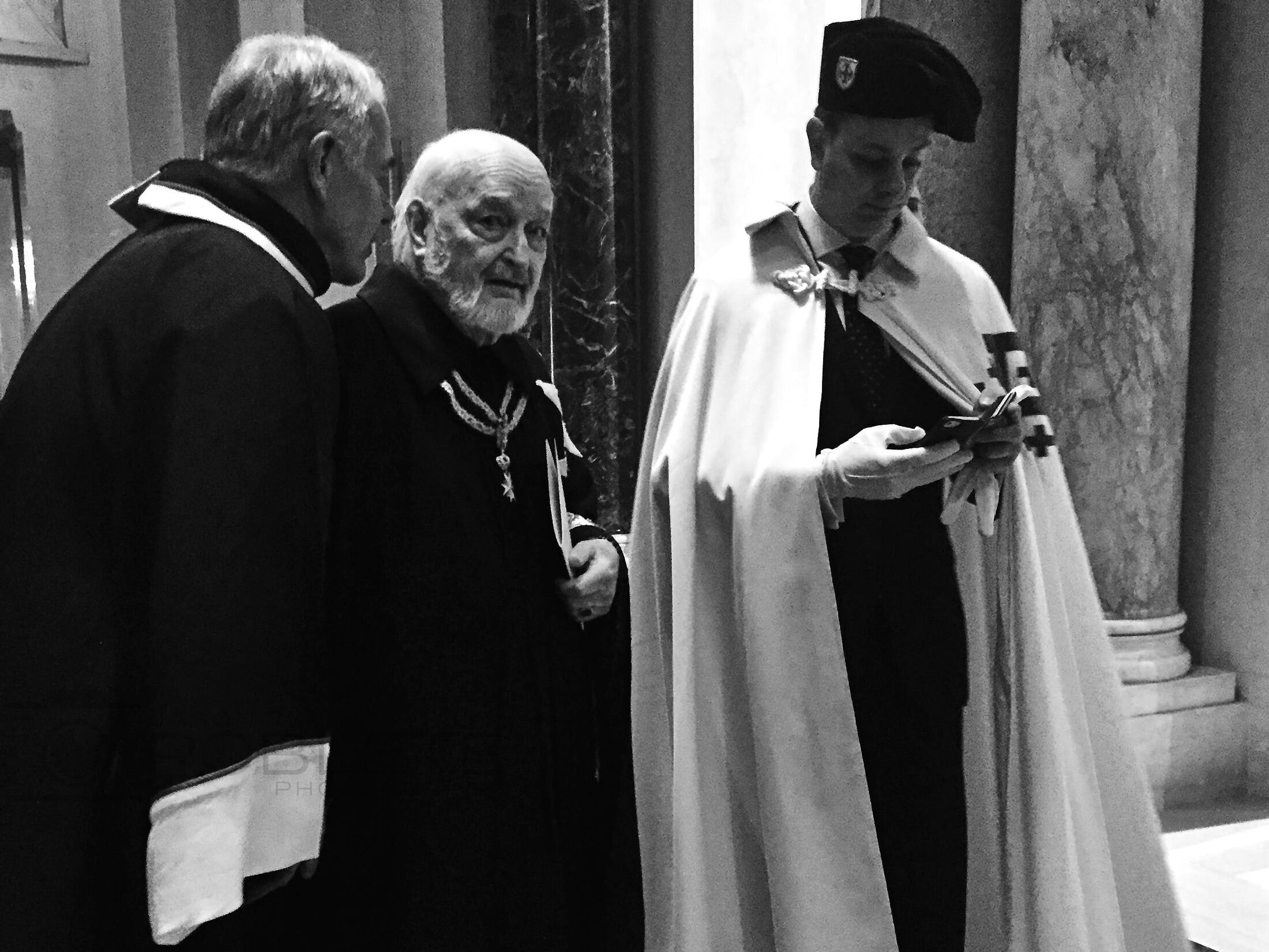 Three clergymen converse during a formal gathering.