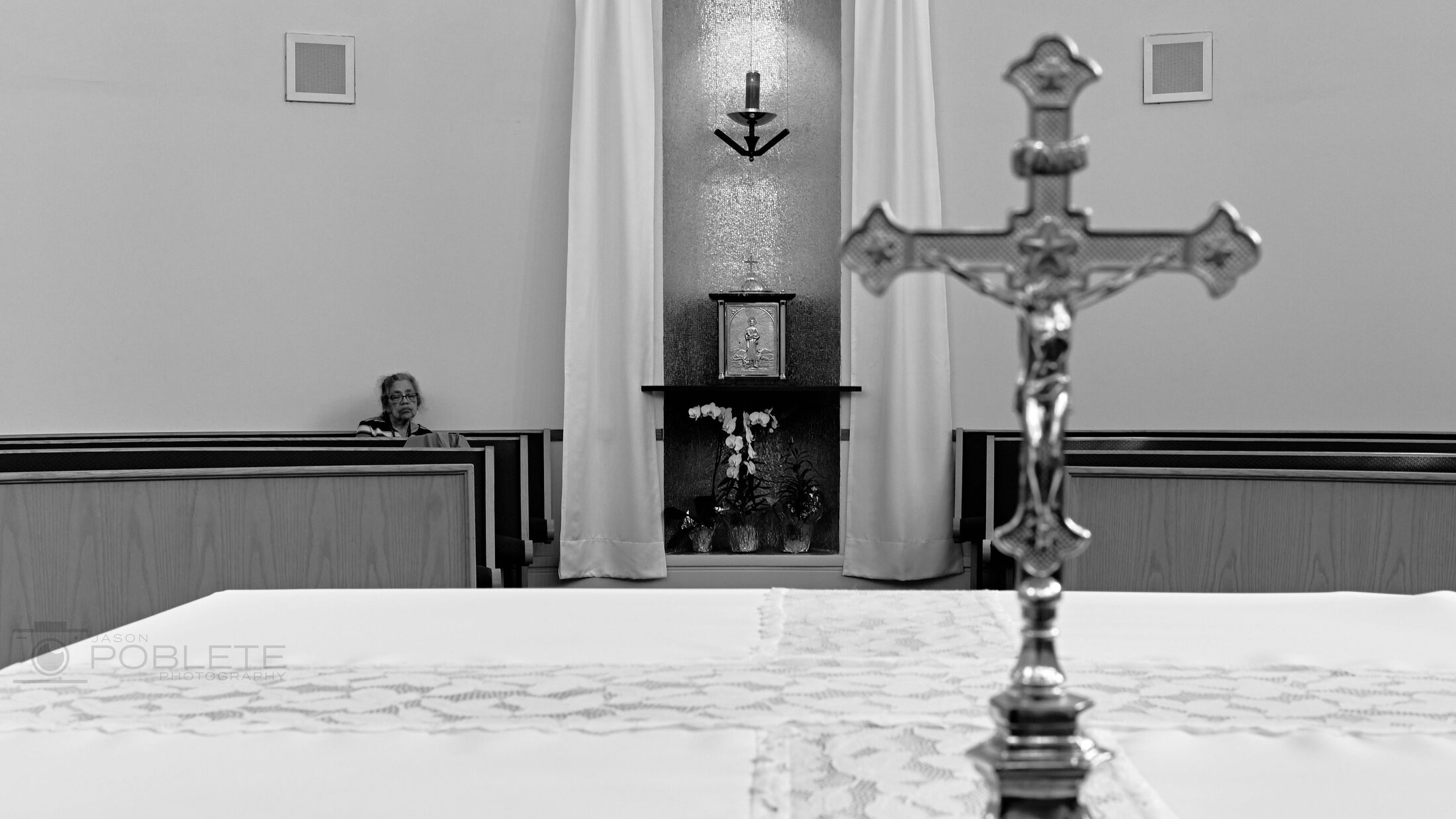A processional cross stands before a simple church altar.