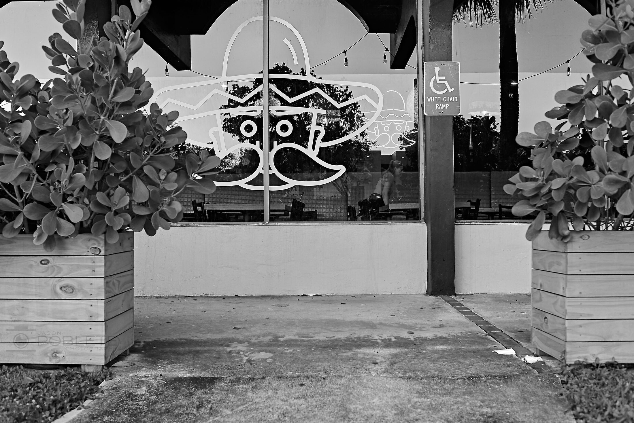 A decorative café sign hangs above an empty outdoor bench.