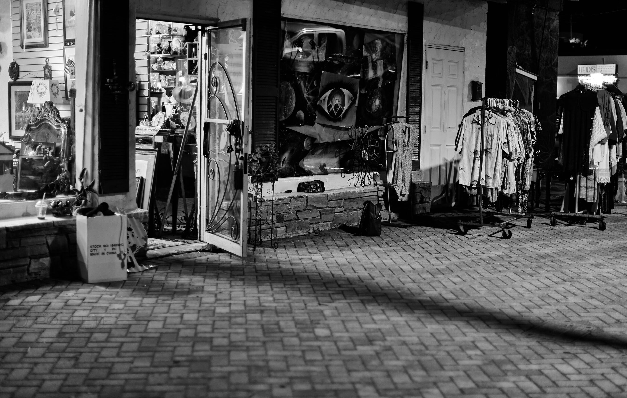 Clothing and goods spill from an open shop onto a brick walkway.