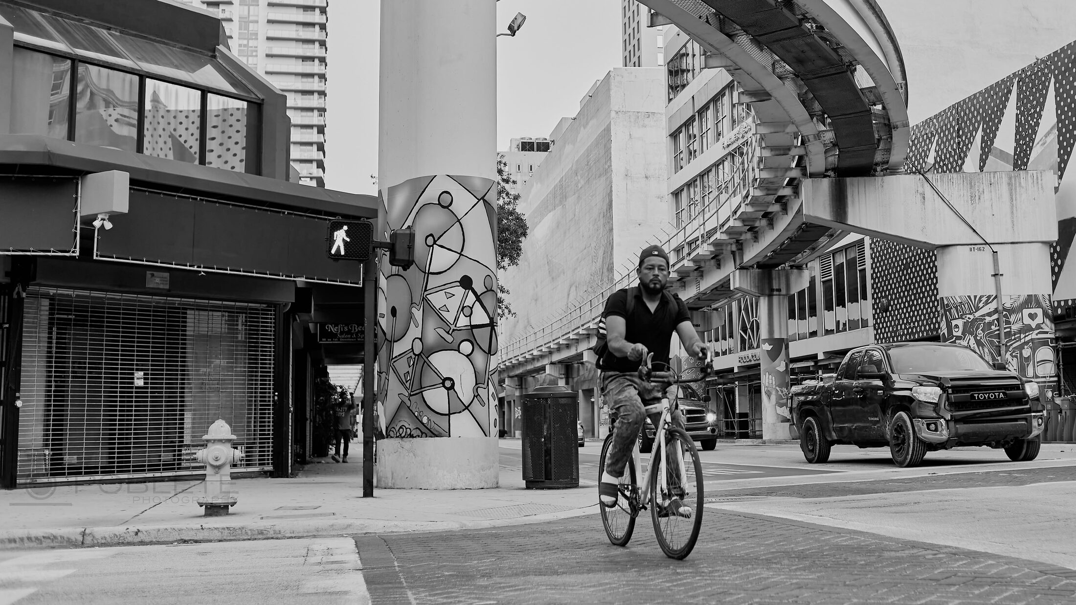 A cyclist rides past storefronts on a city street.