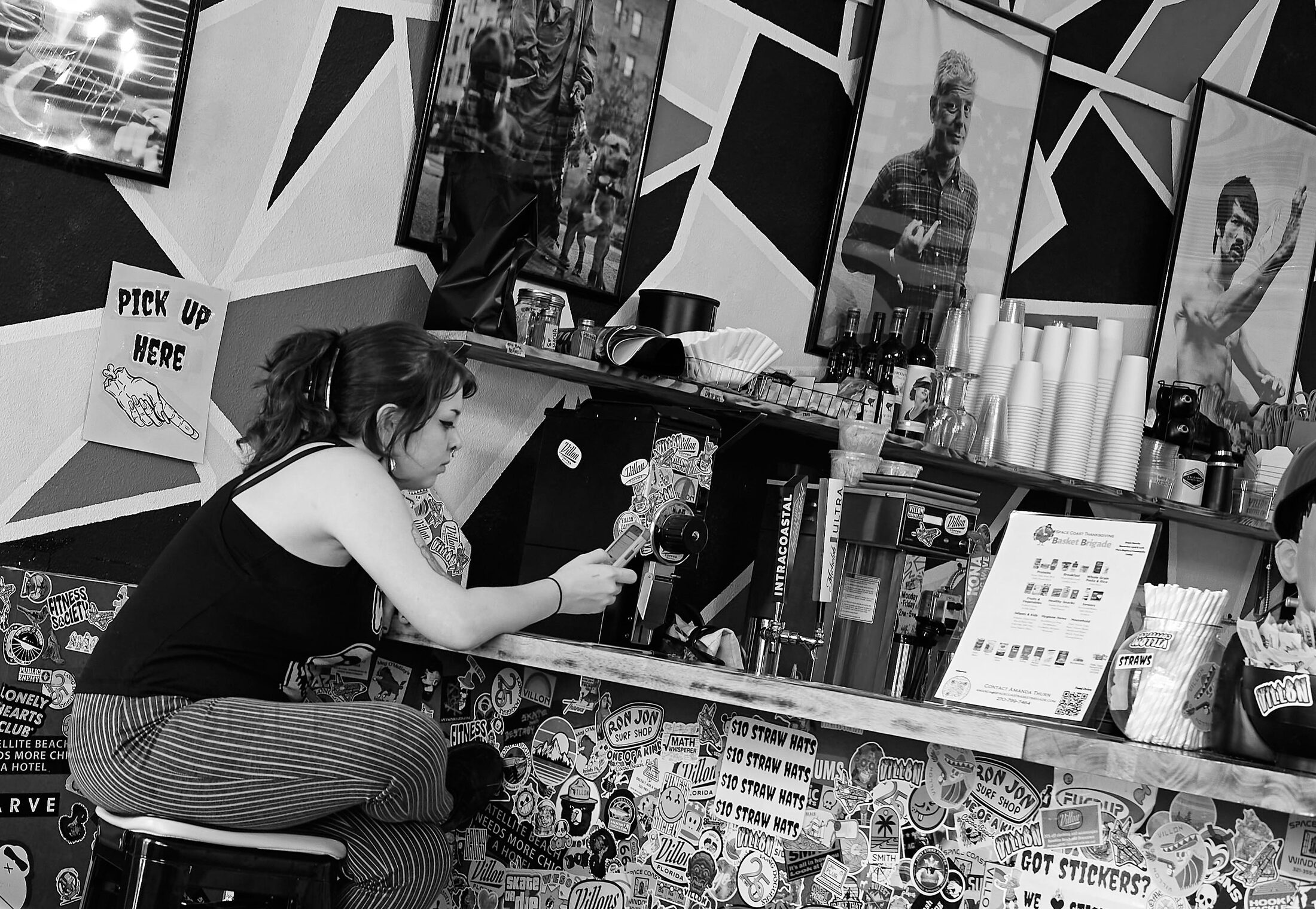 A seated vendor works amid signs, papers, and small goods.