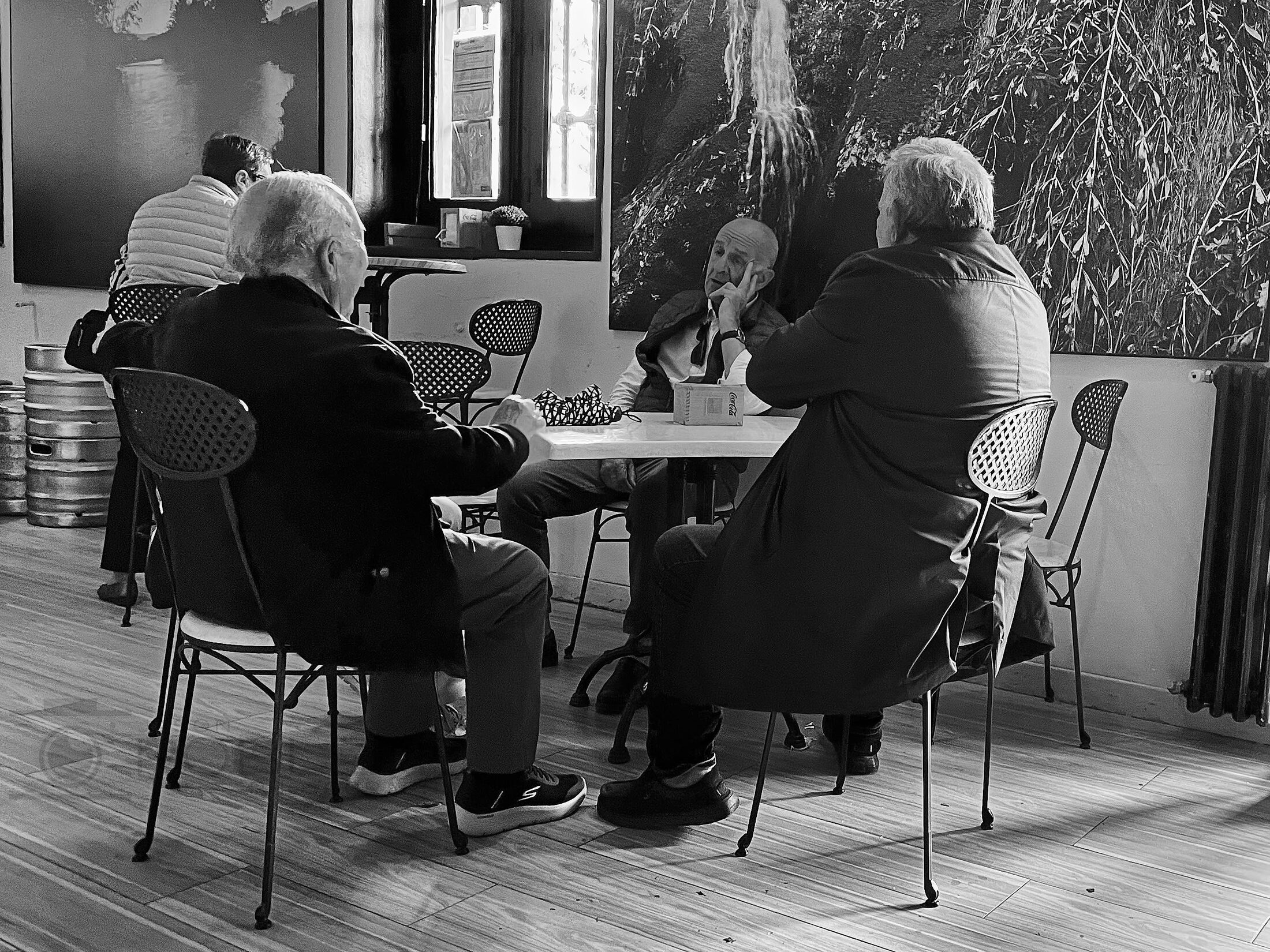 Older adults sit around tables in a bright community room.
