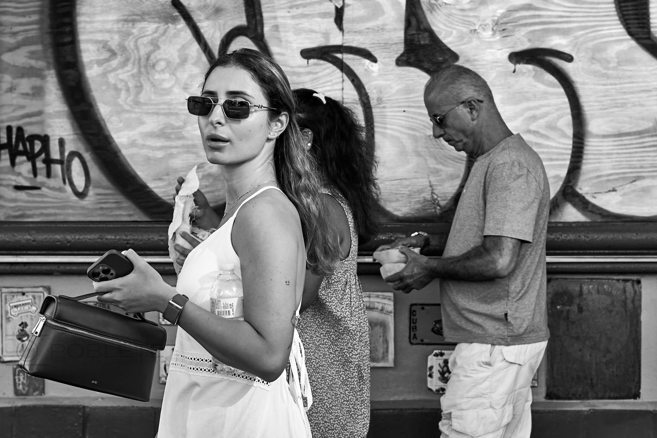 A woman wearing sunglasses sits before a painted mural.