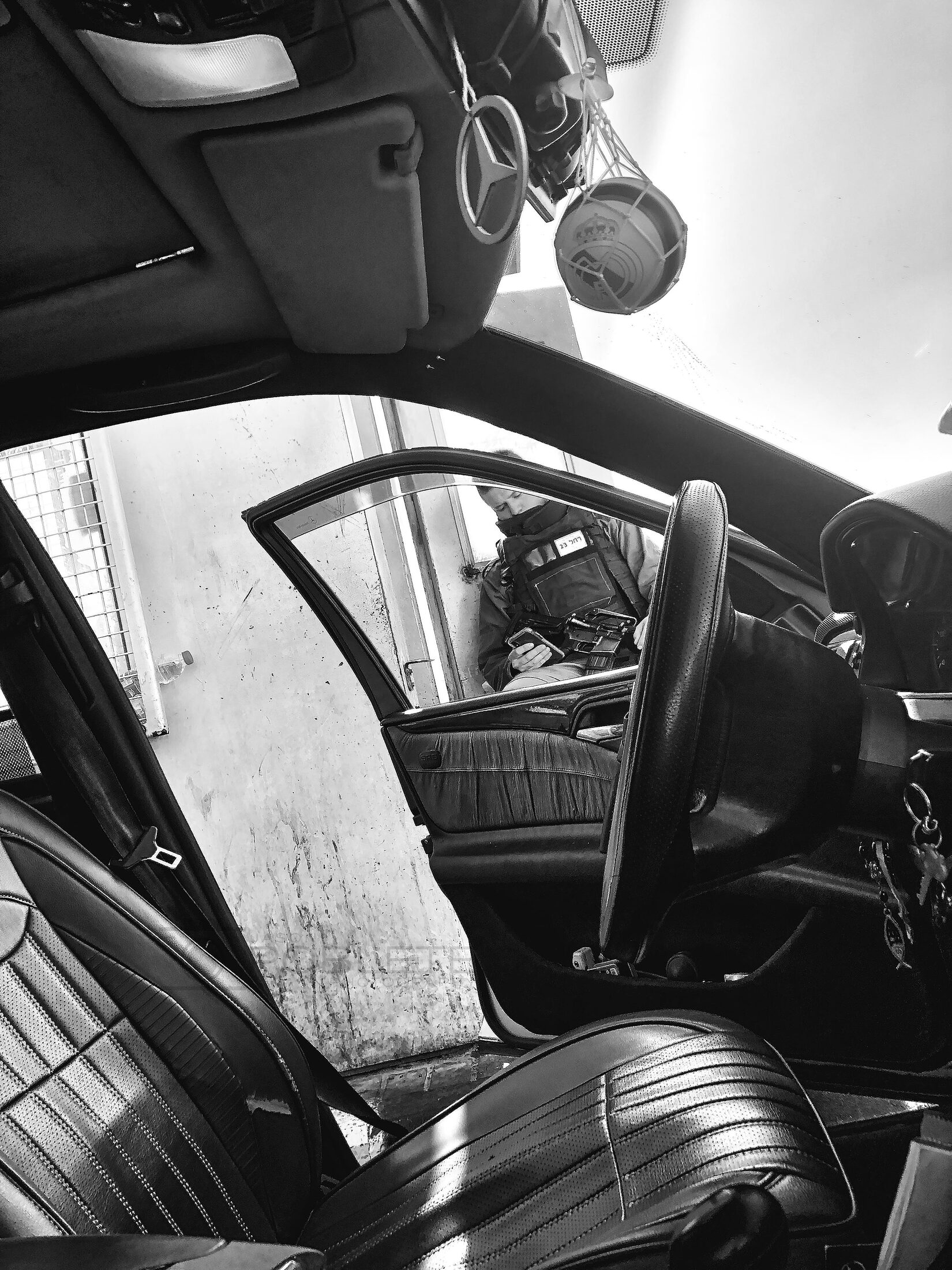 The interior of a car frames a uniformed officer standing outside the open driver-side door.