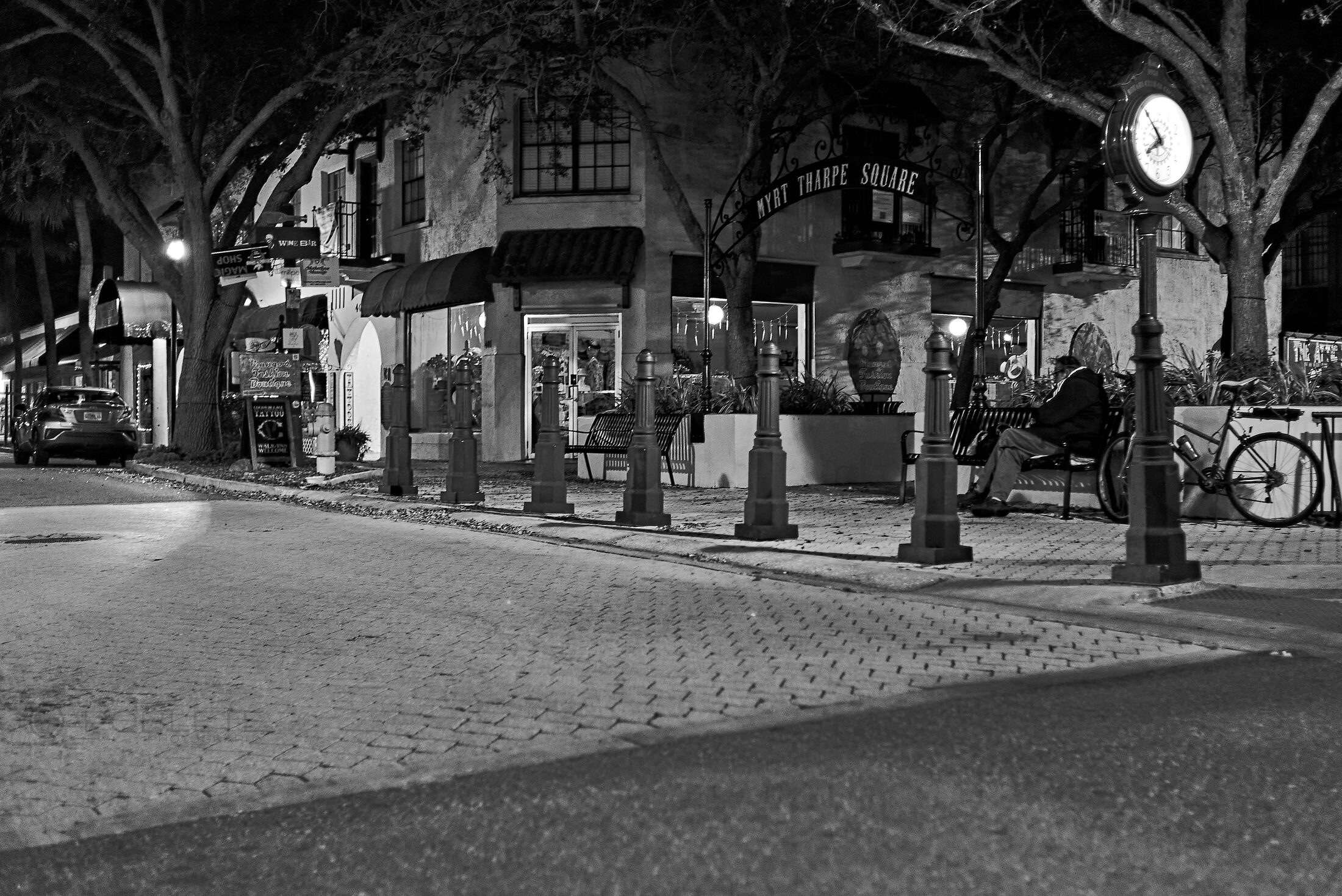 A quiet city intersection is illuminated by streetlights at night.