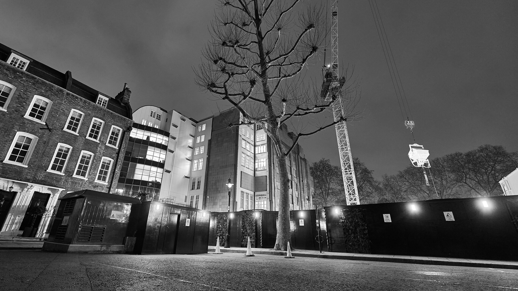 A low night view looks across a city street toward lit buildings.
