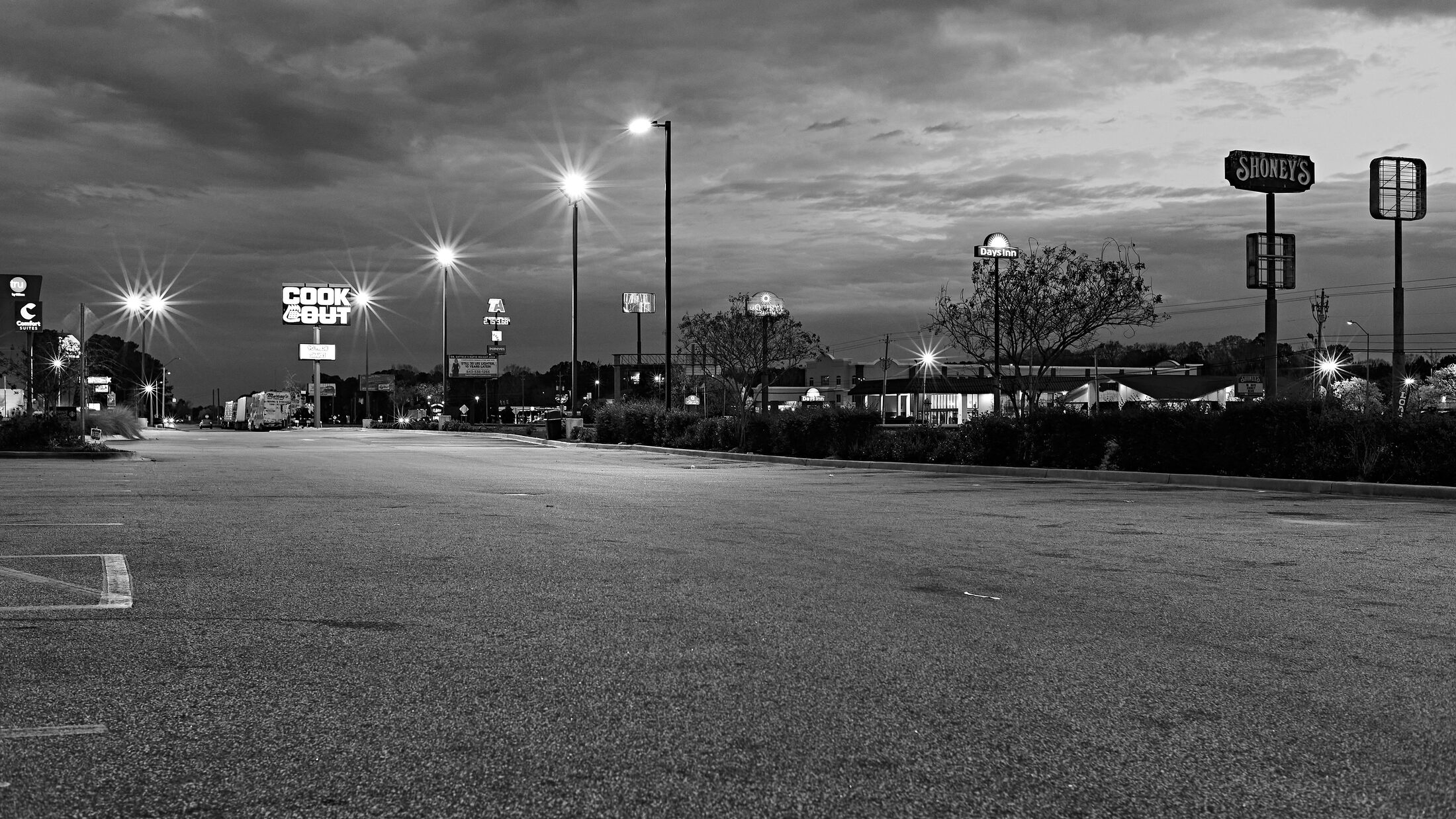 An empty parking lot glows beneath rows of overhead lights.