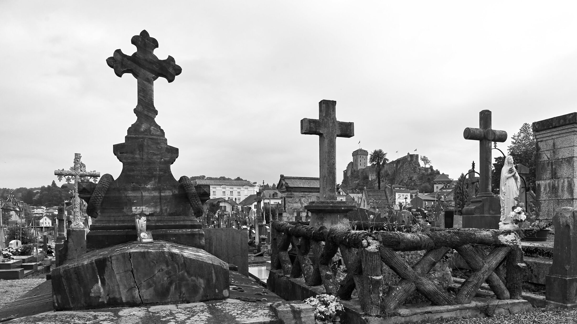 Stone crosses rise above crowded graves under an overcast sky.