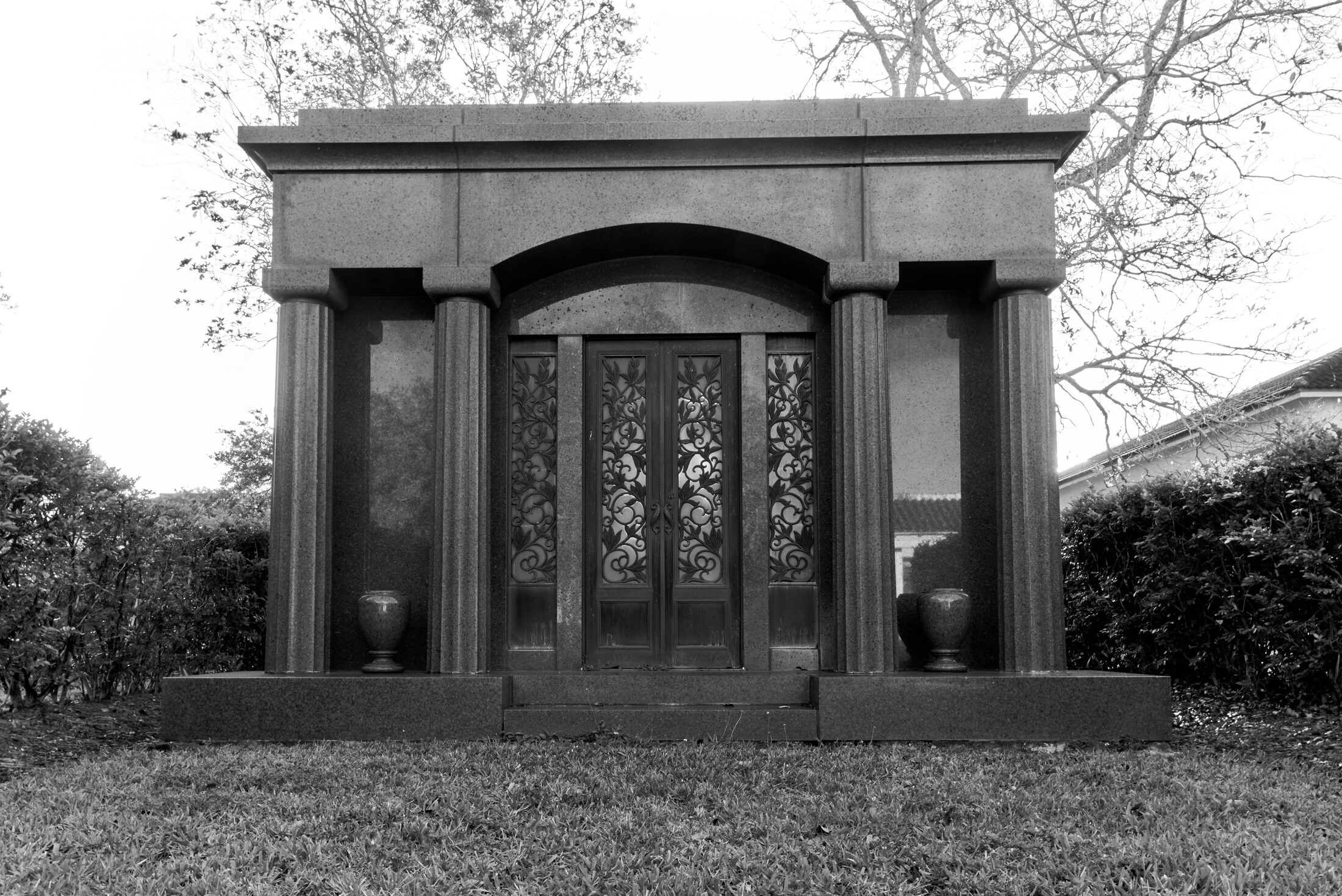A dark stone mausoleum stands beneath bare trees.