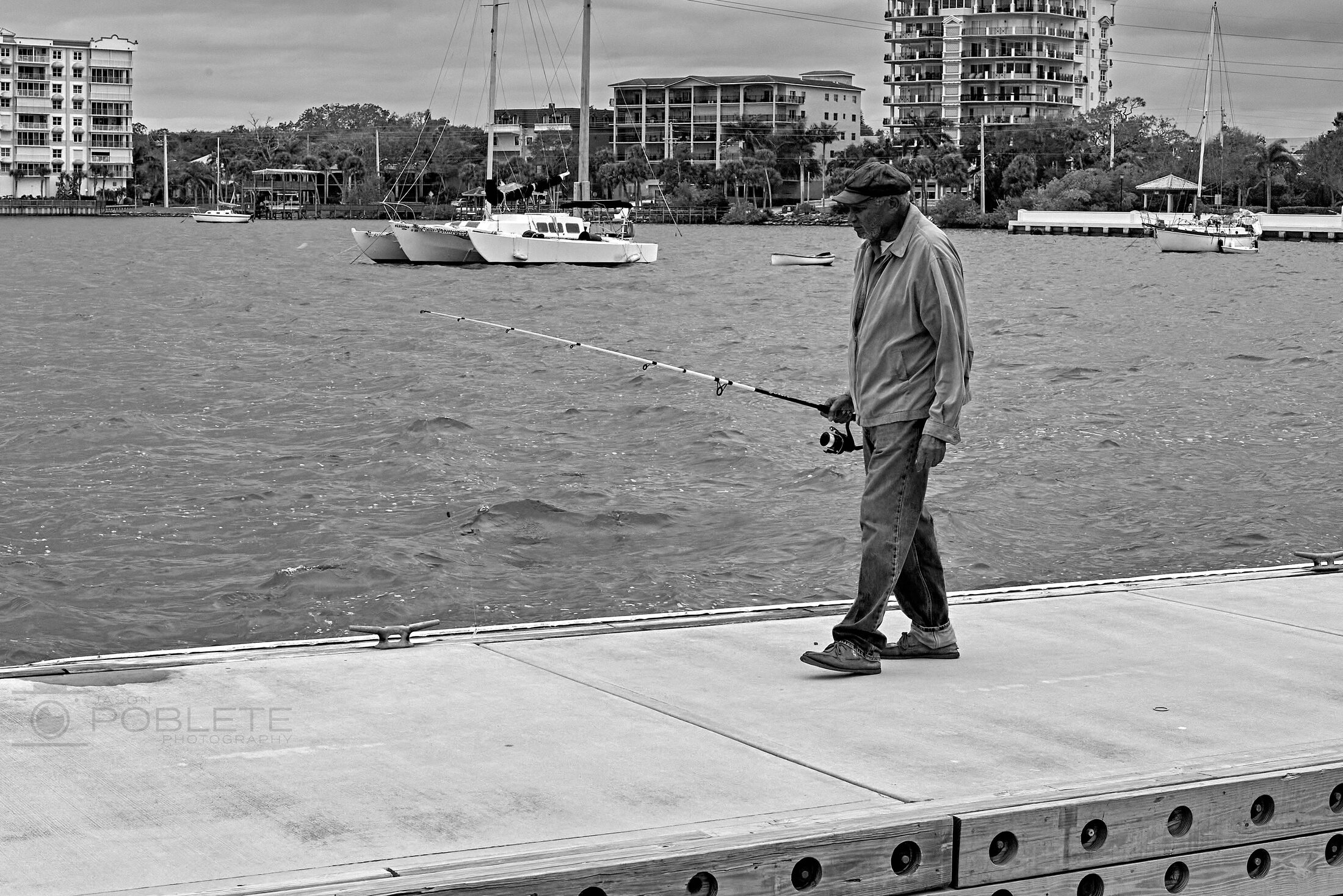 A fisherman stands at the edge of a concrete waterfront.